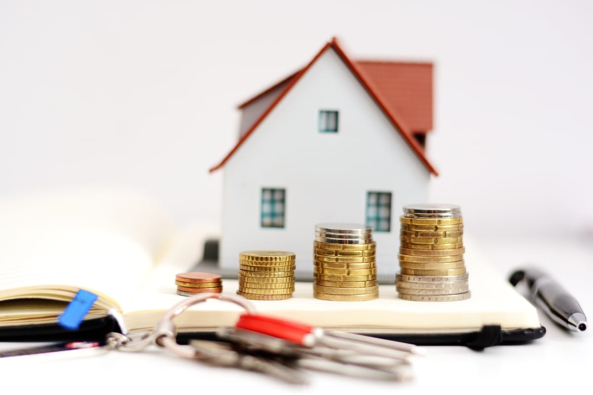 A small house model, stacks of coins, and keys accompany a pen on an open notebook, reflecting the meticulous process of an HVAC real estate inspection.