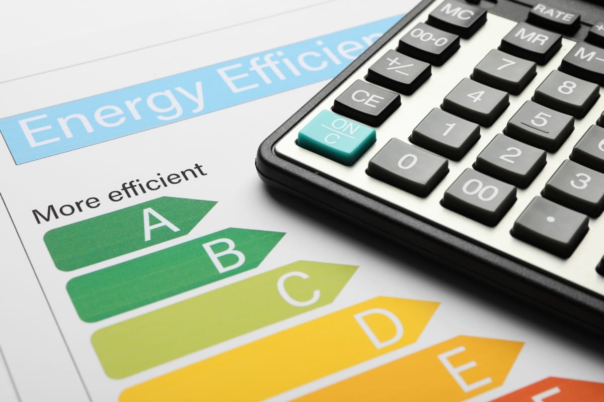 A calculator rests on an energy efficiency rating chart, highlighting labels from A (green, most efficient) to E (orange, least efficient), emphasizing the importance of environmental conservation in everyday choices.