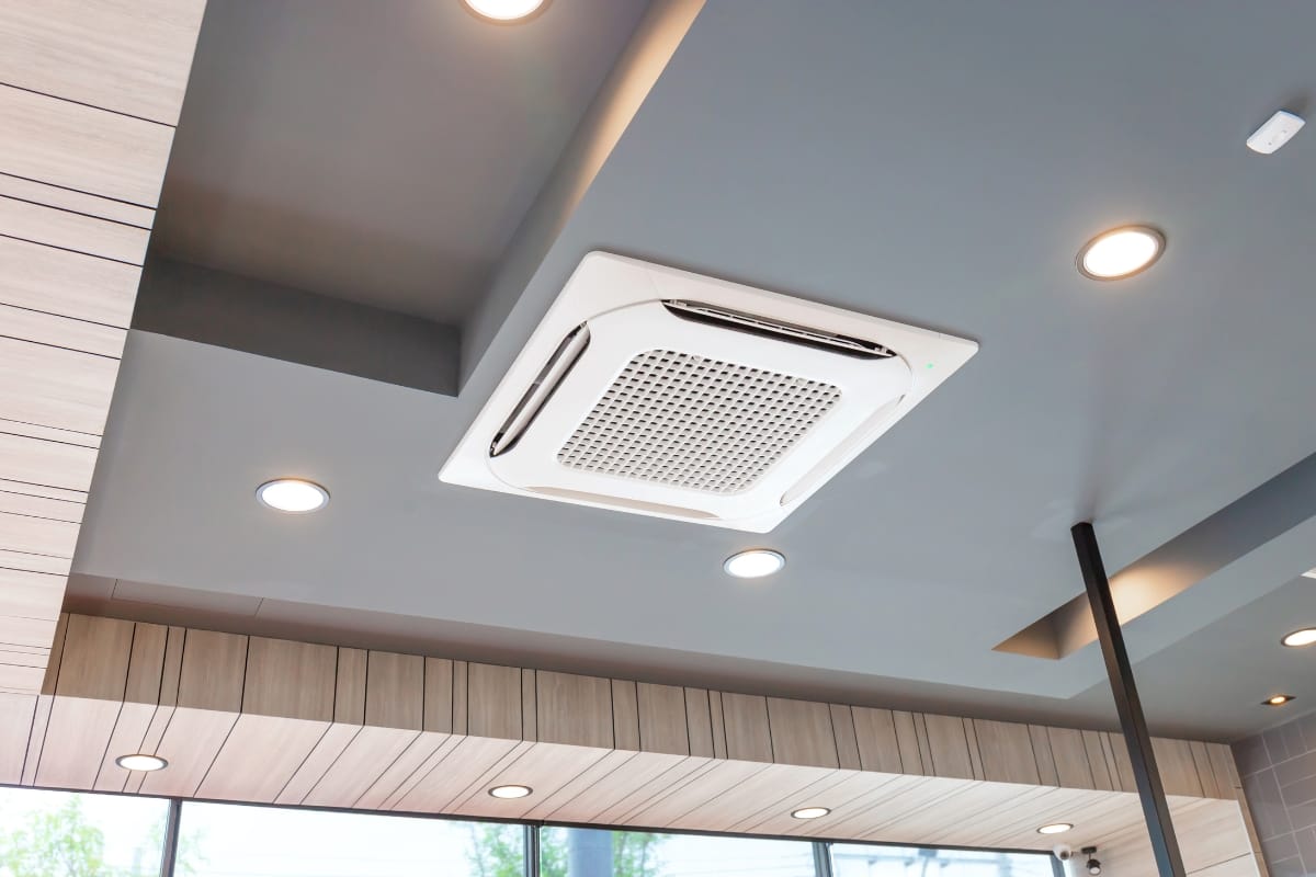 Ceiling-mounted air conditioning unit, designed with environmental conservation in mind, surrounded by recessed lighting in a modern interior space.