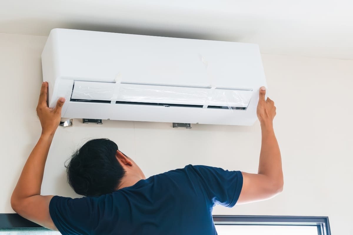 A person installing or adjusting a wall-mounted unit ensures optimal comfort—an essential step for those seeking the best air conditioners for their space.