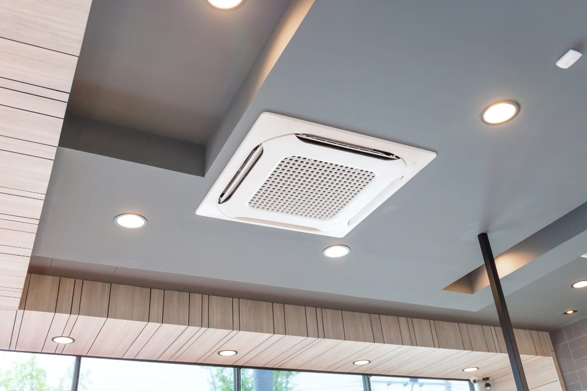 Ceiling-mounted cassette air conditioner with multiple vents and advanced humidity control, surrounded by recessed lighting in a modern indoor space.