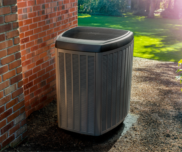 A hvac unit in front of a brick wall. A hvac unit in front of a brick wall.