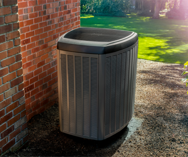 A hvac unit in front of a brick wall.