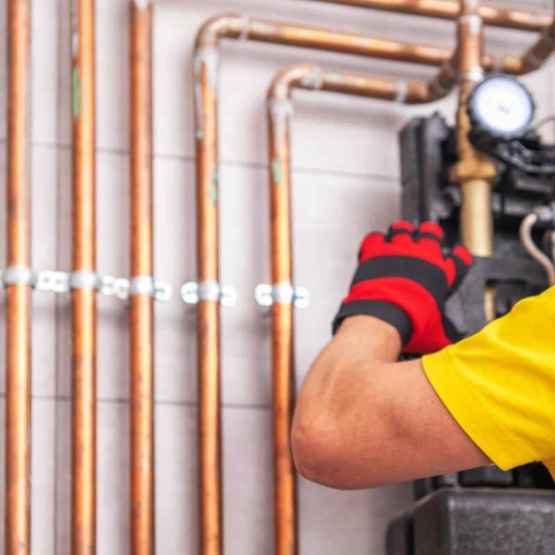 A plumber performing furnace repair on a hot water heater.