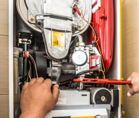 A man performing furnace repair on a hot water heater. A man performing furnace repair on a hot water heater.