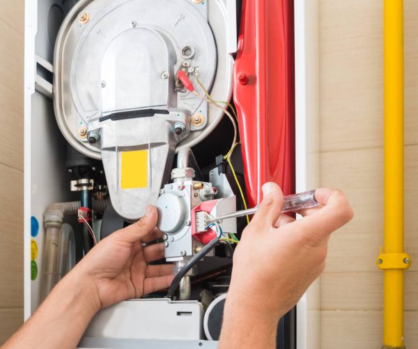 A man conducting furnace repair in a bathroom. A man conducting furnace repair in a bathroom.
