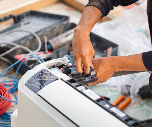 A man is repairing an air conditioning unit.