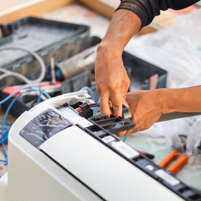 A man is repairing an air conditioning unit.