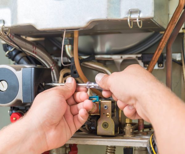 A technician performing furnace repair on a gas furnace.