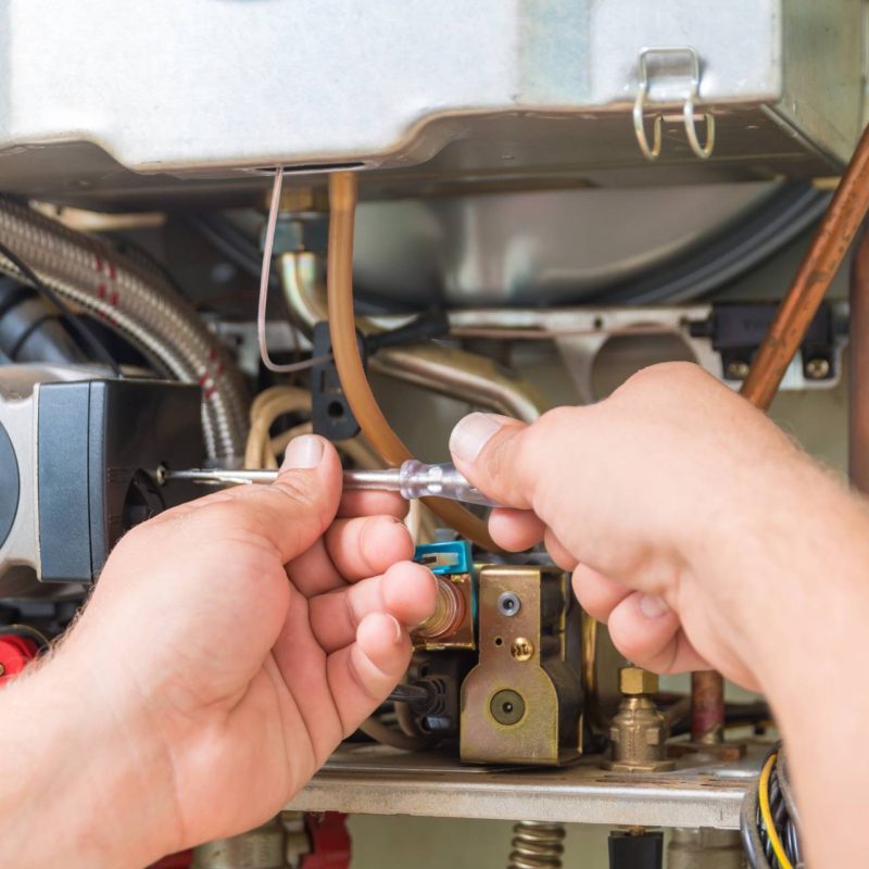 A technician performing furnace repair on a gas furnace.