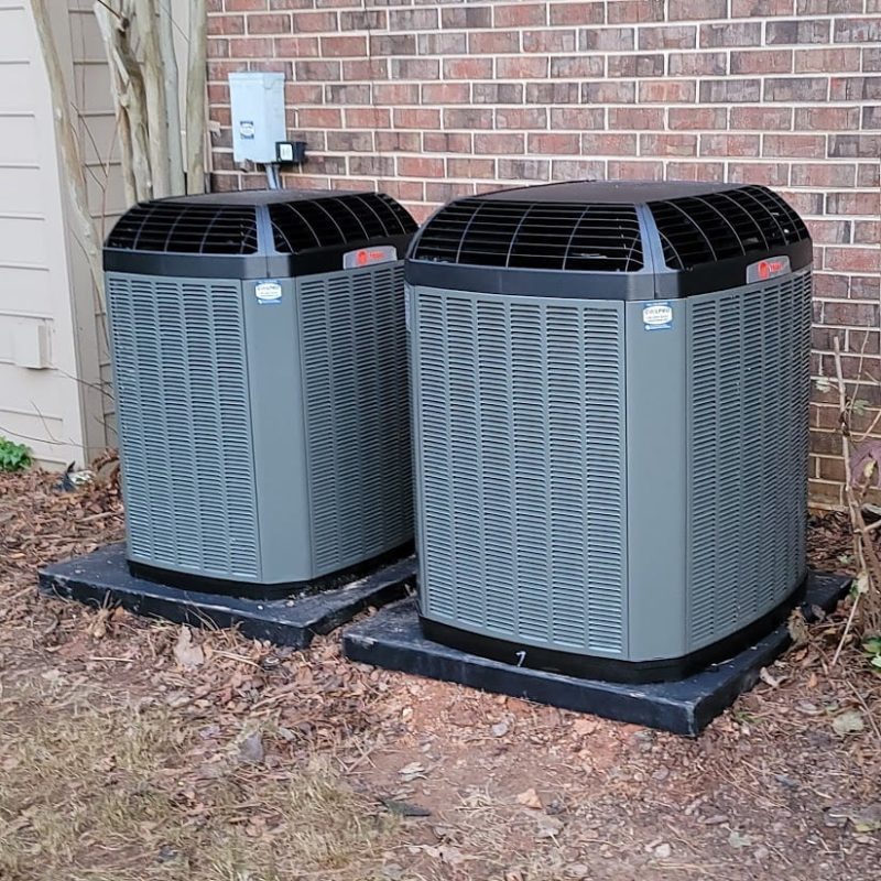 Two air conditioners outside a brick home.