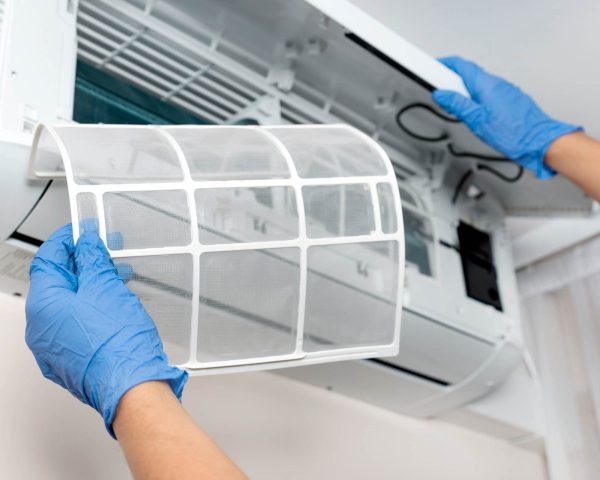 A person is replacing a filter in an air conditioner.