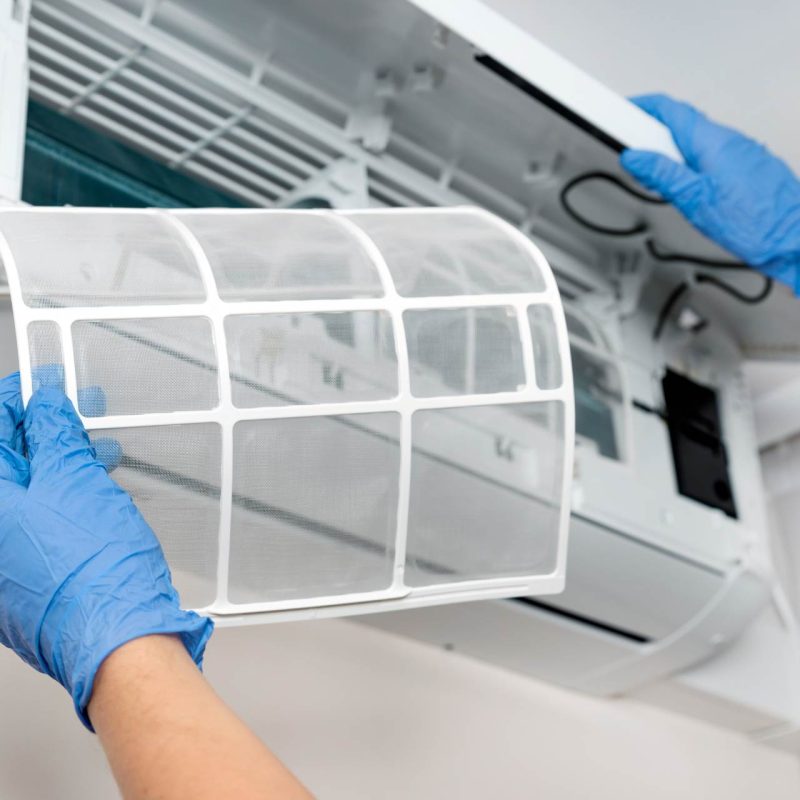 A person is replacing a filter in an air conditioner.