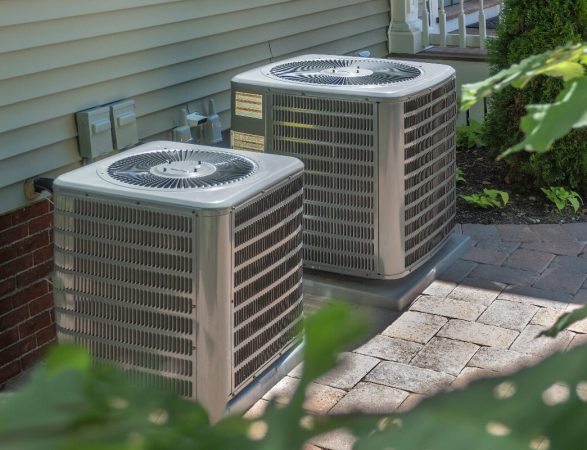 Two air conditioners in front of a house.