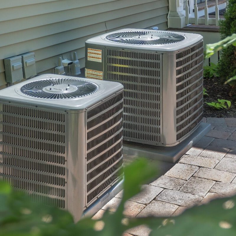 Two air conditioners in front of a house.