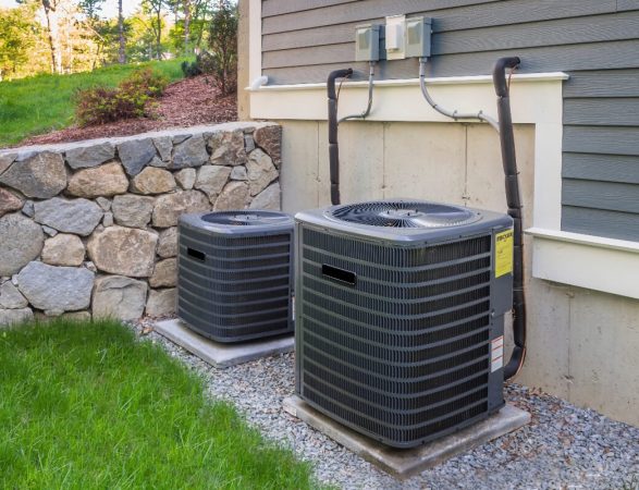 Two air conditioners on the side of a house.